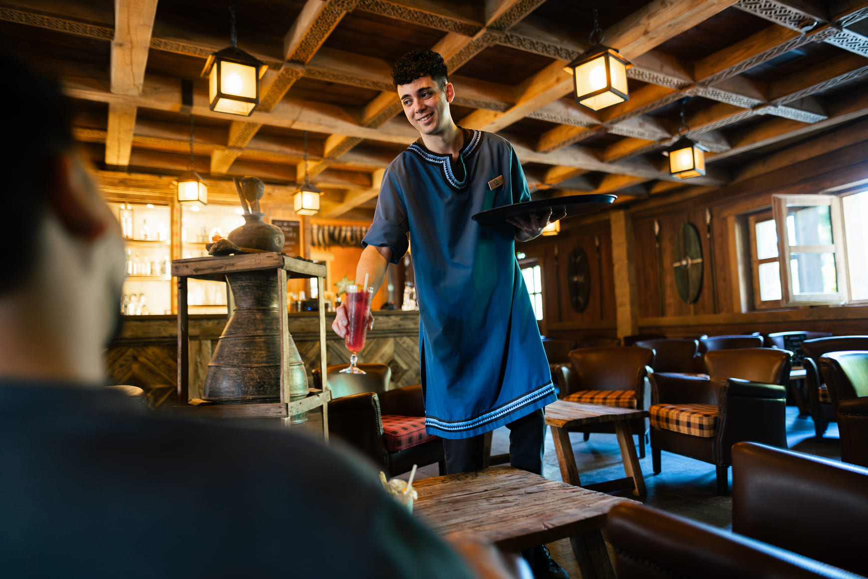 Un barman sert des boissons à plusieurs clients dans un bar du Parc Astérix.