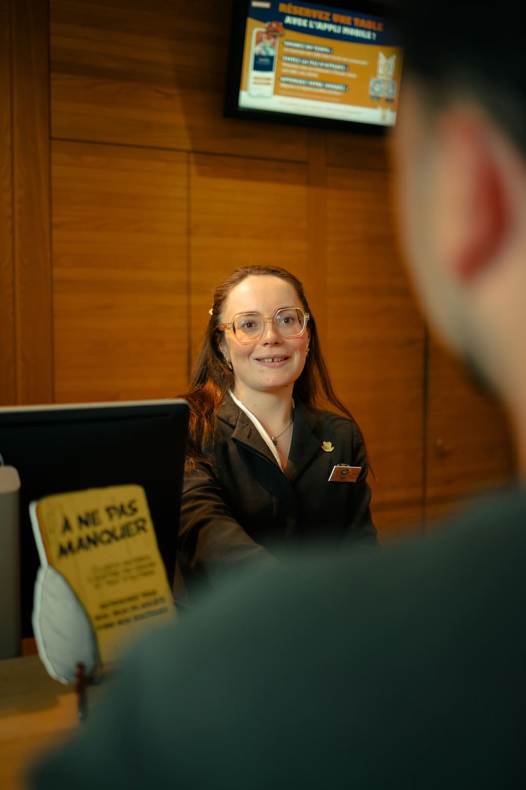 Une réceptionniste conseille un client dans un hôtel du Parc Astérix.
