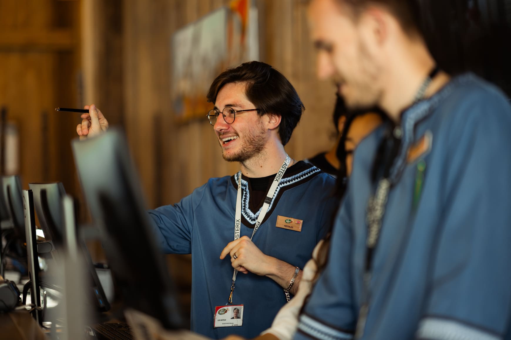 Un réceptionniste conseille un client au comptoir de réception d’un hôtel du Parc Astérix.