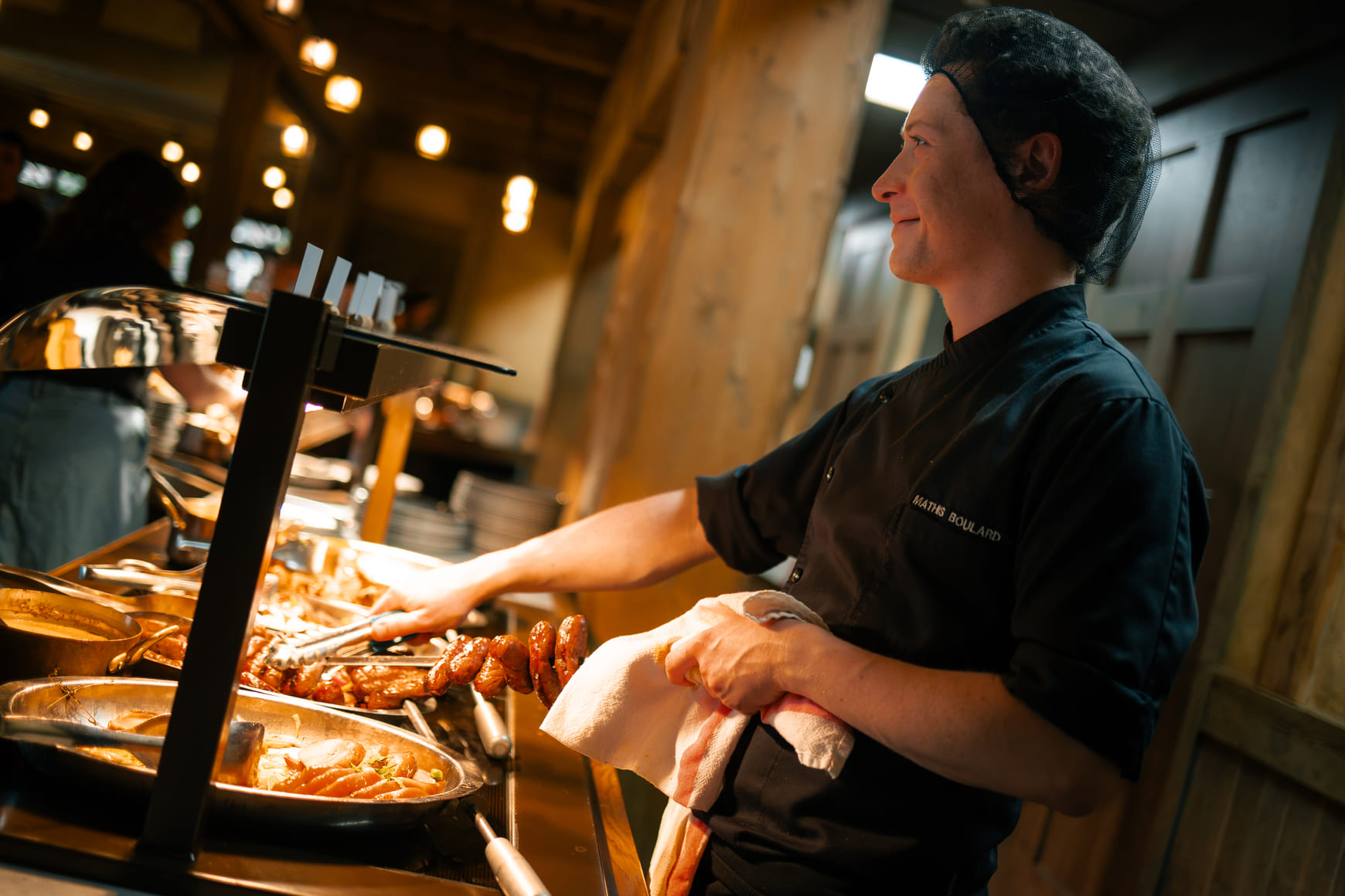 Un second de cuisine sert un client dans le restaurant d’un hôtel du Parc Astérix.