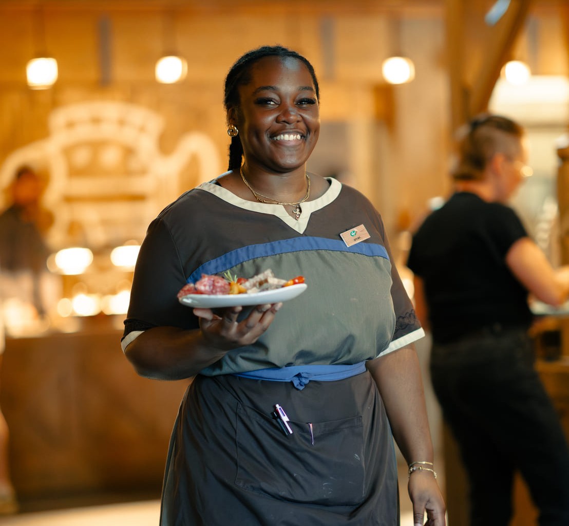 Une serveuse apporte une assiette à une table dans le restaurant d’un hôtel du Parc Astérix.
