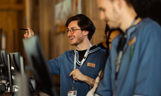 Un réceptionniste conseille un client au comptoir de réception d’un hôtel du Parc Astérix.