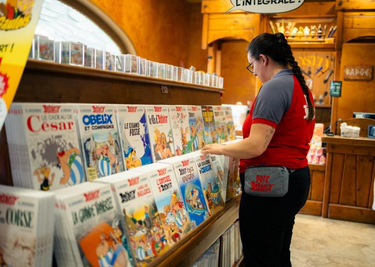 Une assistante manager boutiques range les bandes dessinées Astérix dans une boutique du Parc.