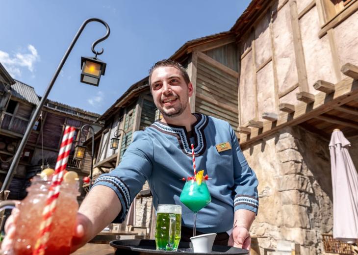 Une barmaid découpe des fruits pour préparer les boissons dans un bar du Parc Astérix.