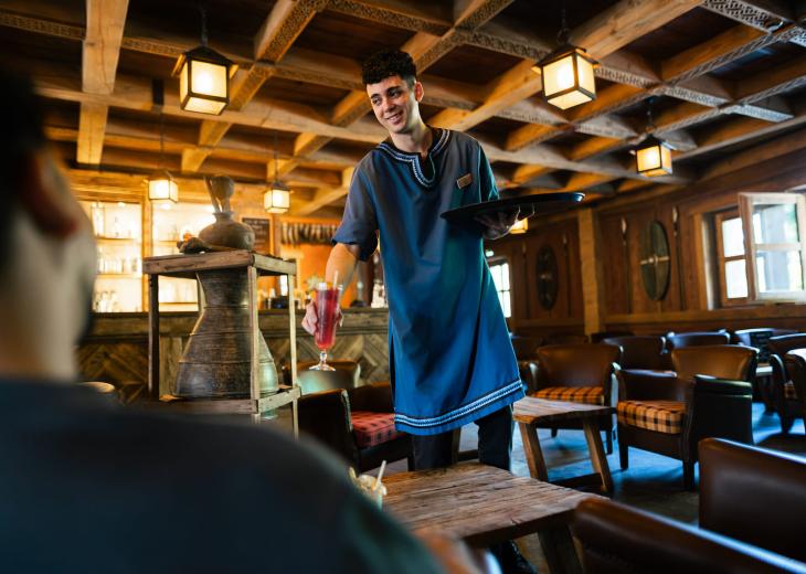 Un barman sert des boissons à plusieurs clients dans un bar du Parc Astérix.