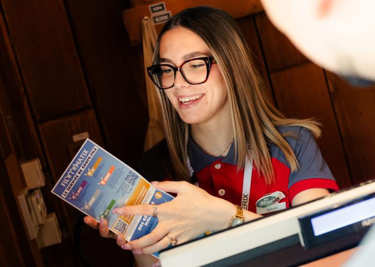 Une conseillère vendeuse renseigne un visiteur à l’aide du plan du Parc Astérix.