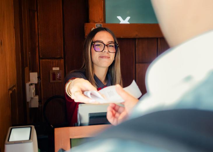 Une conseillère vendeuse remet son ticket à un client dans une boutique du Parc Astérix.