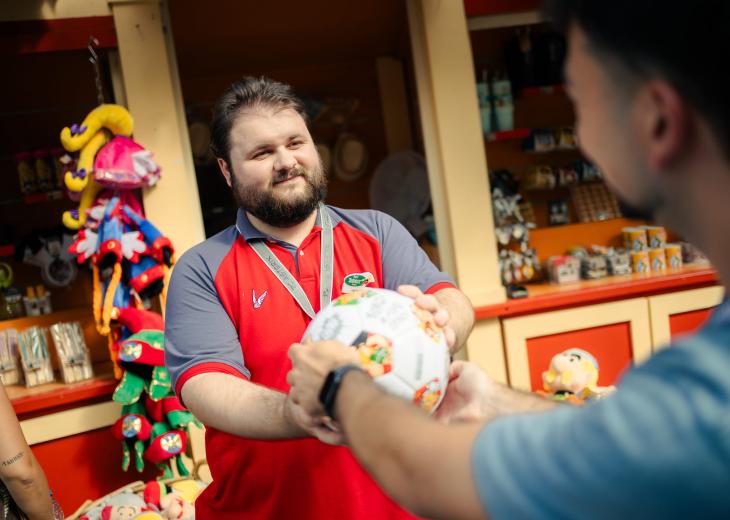 Un conseiller vendeur renseigne un client dans une boutique du Parc Astérix.