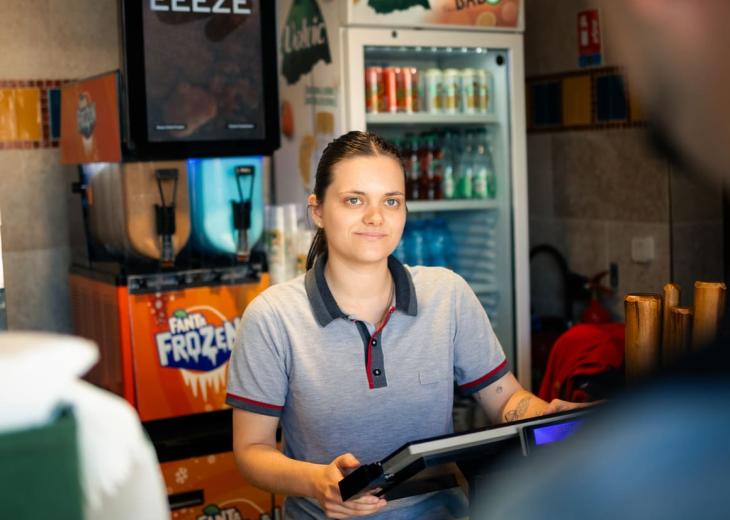 Une manager en restauration sert des clients dans un restaurant du Parc Astérix.