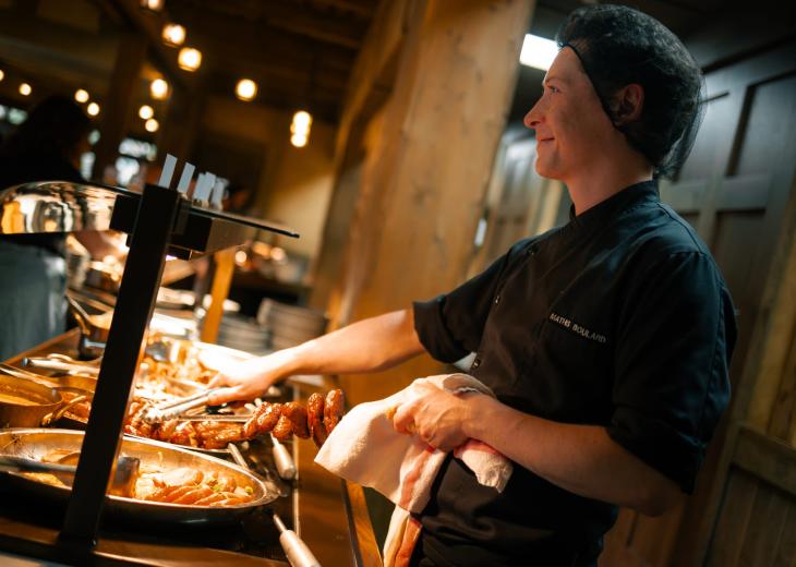 Un second de cuisine sert un client dans le restaurant d’un hôtel du Parc Astérix.