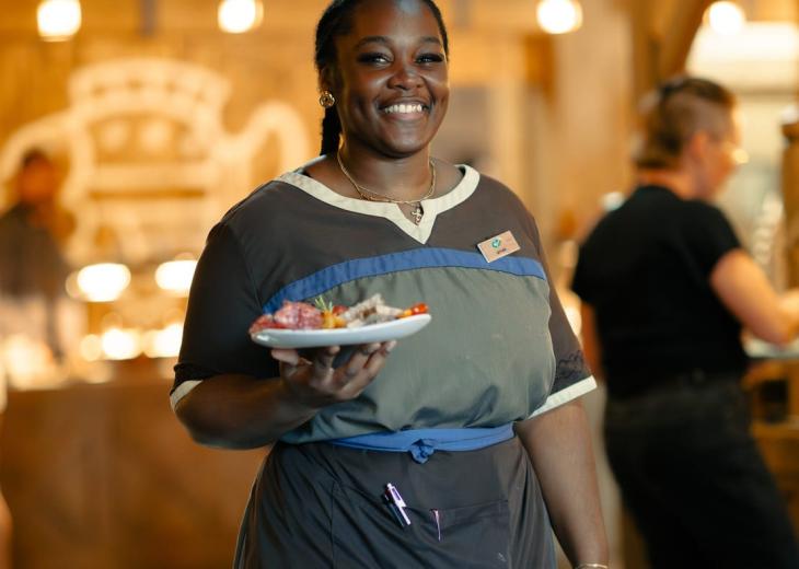 Une serveuse apporte une assiette à une table dans le restaurant d’un hôtel du Parc Astérix.