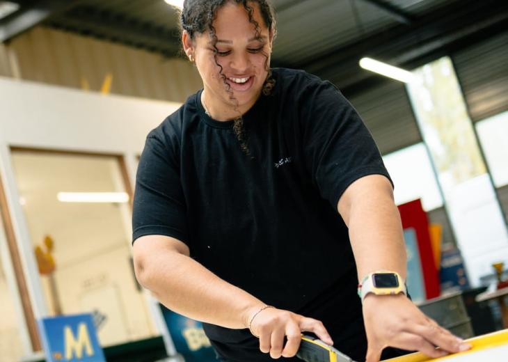 Une technicienne signalétique découpe des adhésifs dans un atelier du Parc Astérix.