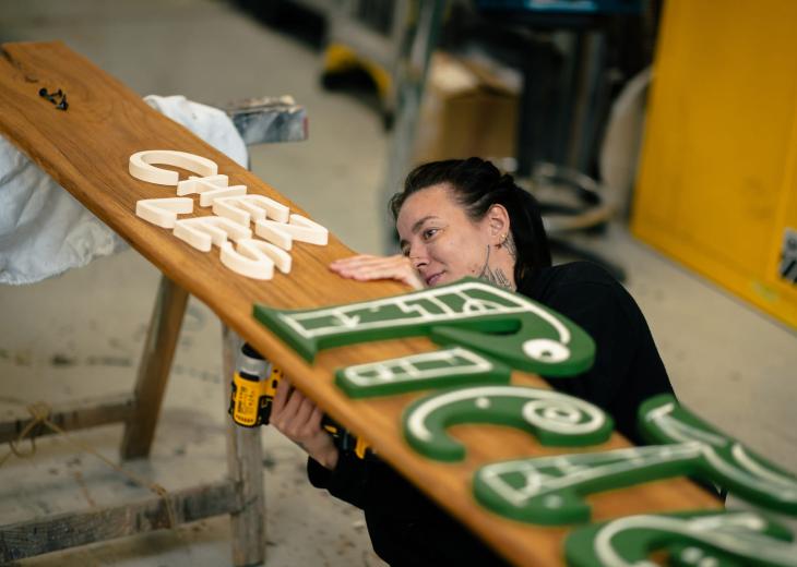 Une technicienne signalétique prépare un panneau décoratif destiné aux décors du Parc Astérix.