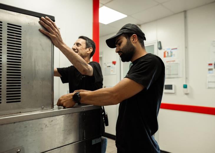 Deux techniciens de maintenance réparent une machine dans un restaurant du Parc Astérix.