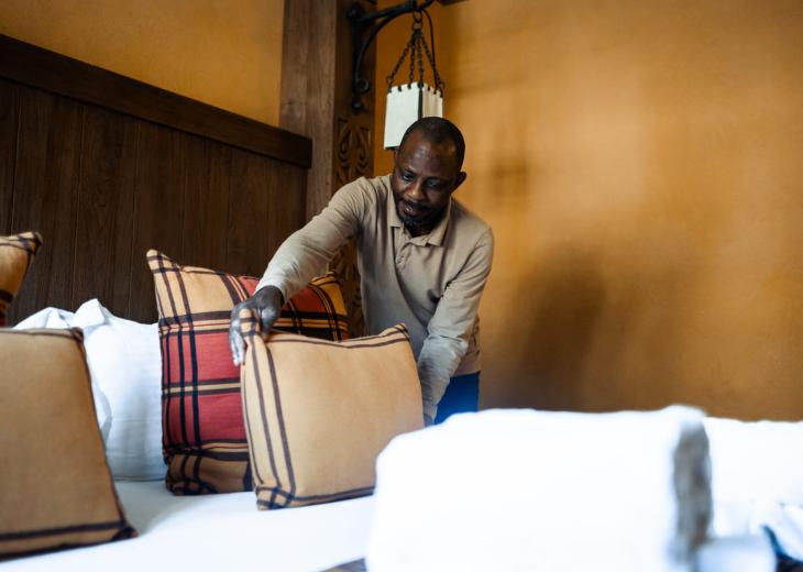 Un valet de chambre prépare un lit dans une chambre d’hôtel du Parc Astérix.